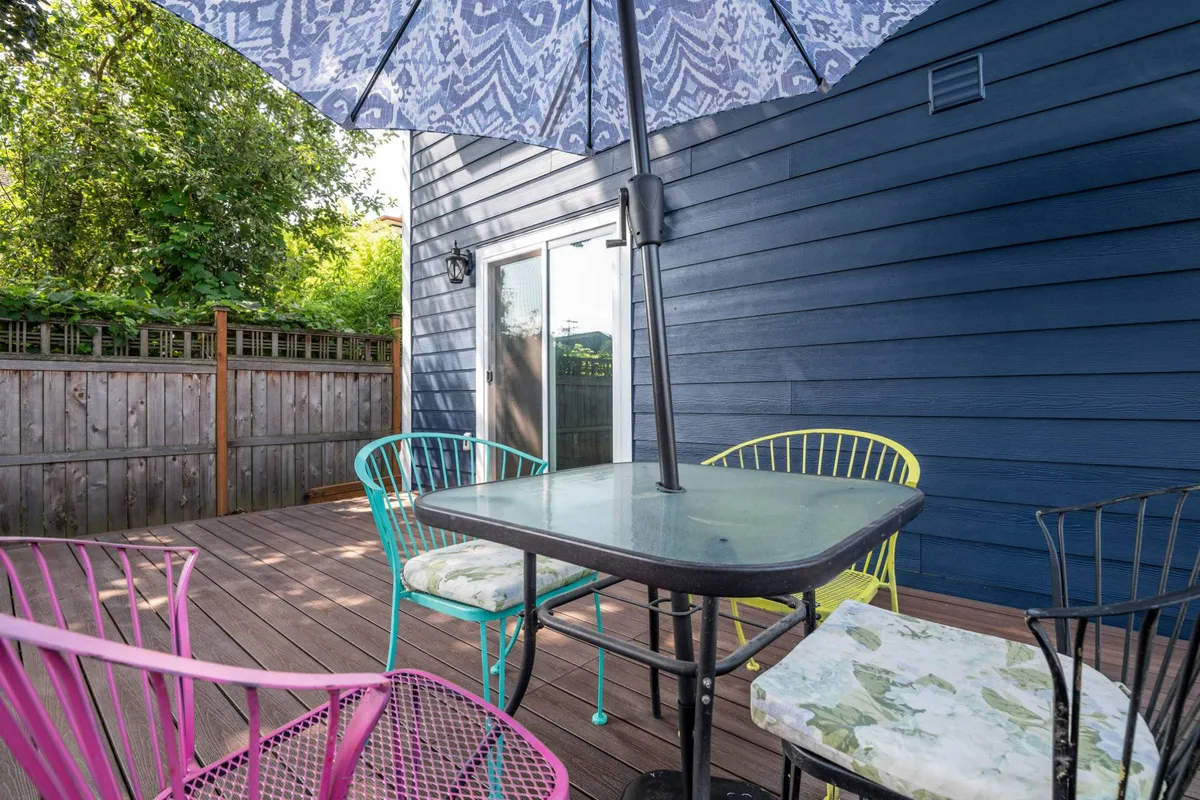 This exterior image features a welcoming outdoor setting with colorful chairs, a table, and an umbrella, creating an inviting space for relaxation, group meals, or socializing. The cheerful mood is accentuated by bright outdoor light and the vibrant setup, suggesting an ideal spot for families or friends to gather between adventures.